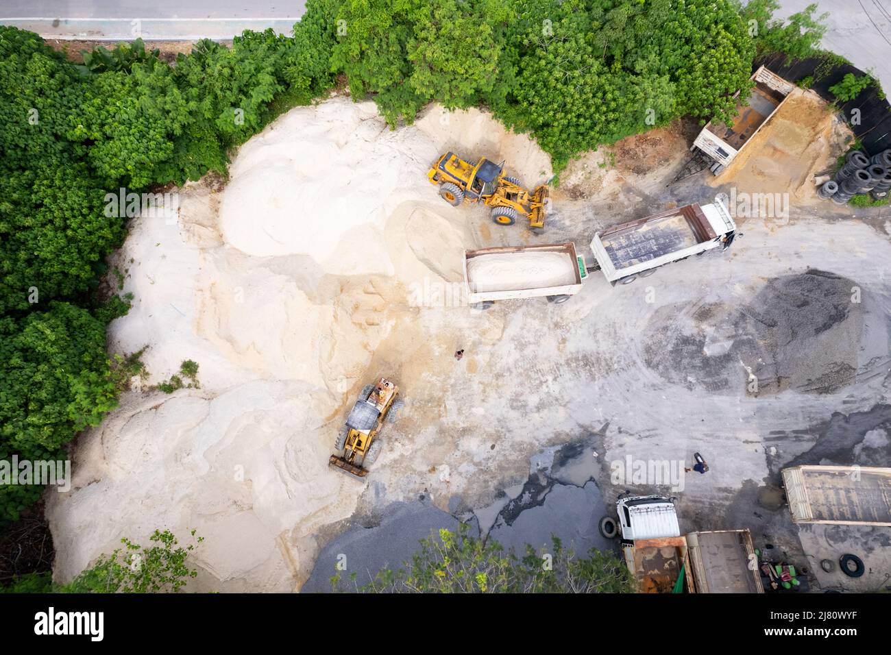 Vista con droni sulla cava di sabbia con macchinari pesanti.il camion e l'escavatore.il camion guida fino all'escavatore per il caricamento di sabbia e pietra frantumata Foto Stock