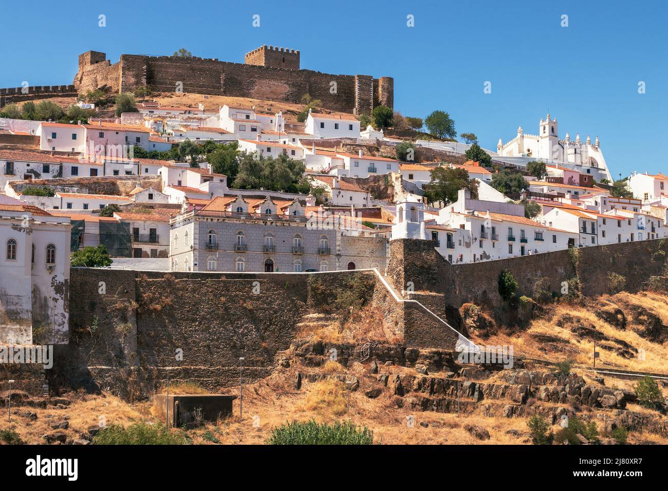 Vista di parte del villaggio di Mértola in Portogallo, evidenziando il suo castello e la chiesa, in una giornata di sole in estate. Foto Stock