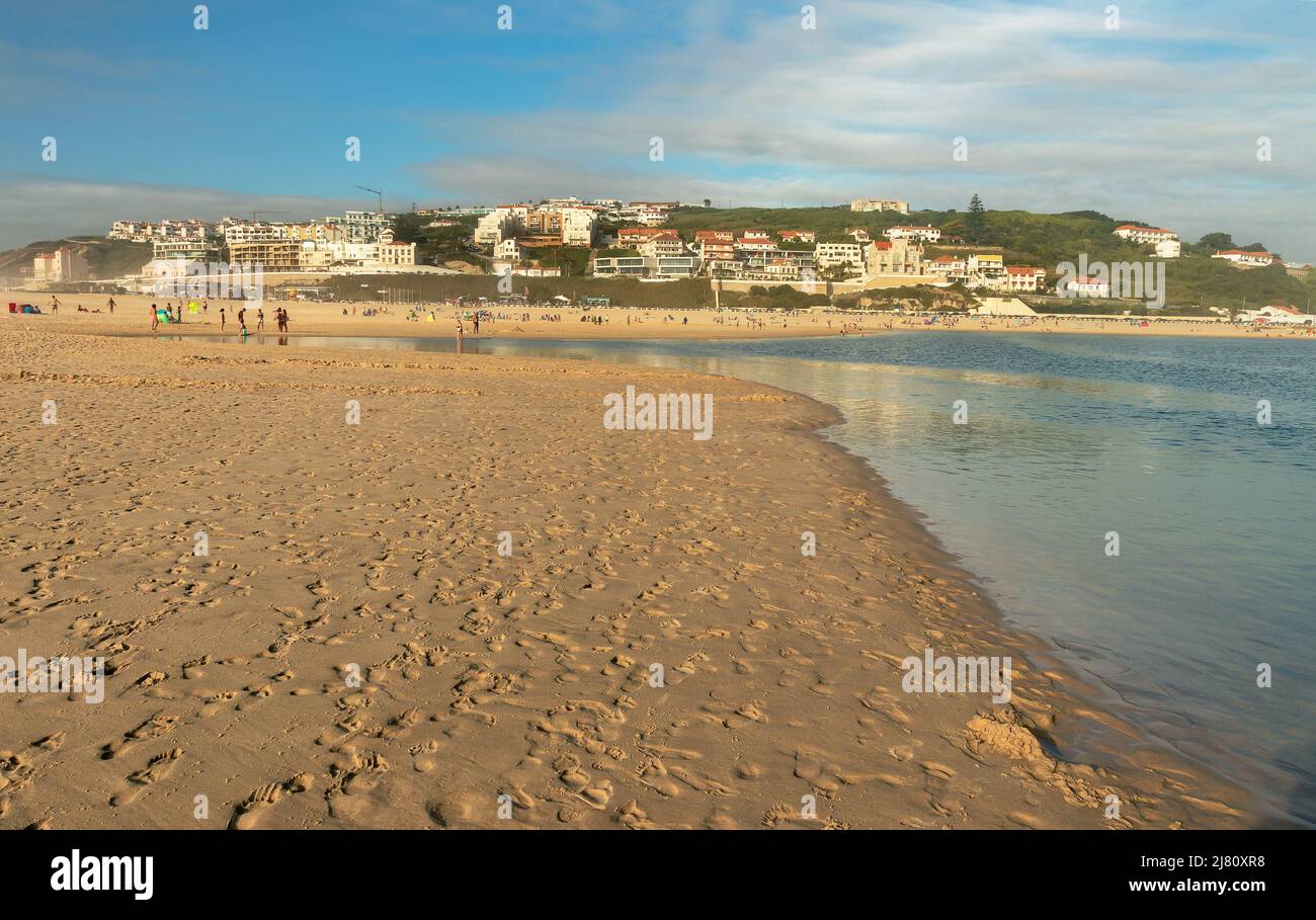 Vista della spiaggia di Foz do Arelho, in Portogallo, dalla sabbia con il villaggio sullo sfondo, in un tardo pomeriggio estivo. Foto Stock