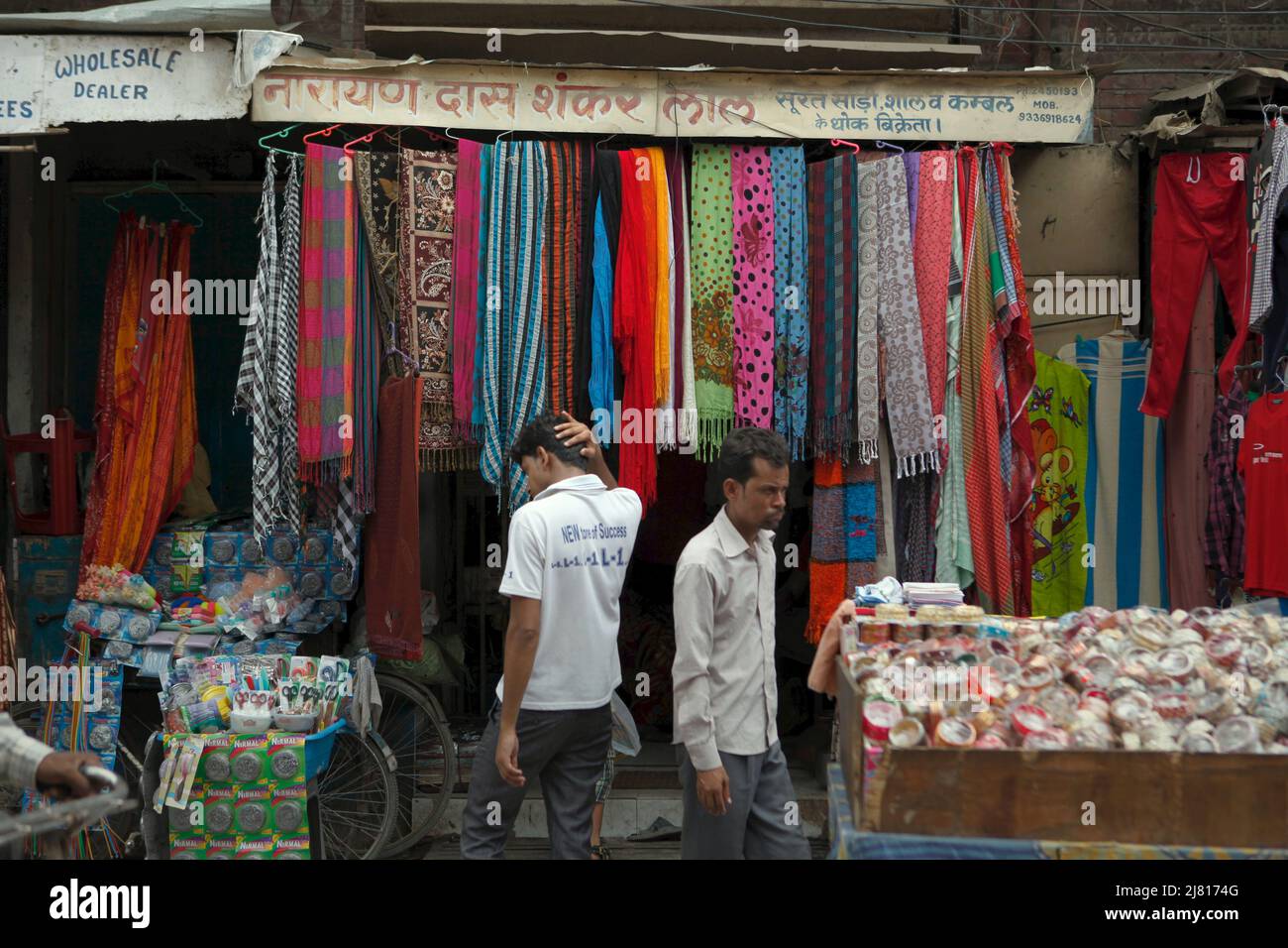 Uomini in piedi di fronte ad un venditore di abbigliamento stradale a Varanasi, Uttar Pradesh, India. Foto Stock