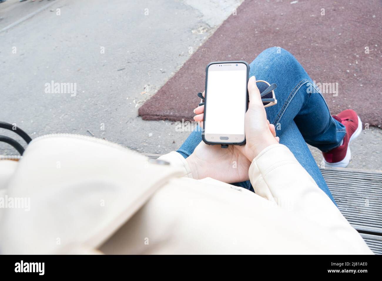 La ragazza tiene in mano uno smartphone con uno schermo bianco per il layout o la pubblicità sul telefono display.A mezzi di comunicazione, comunicazione Foto Stock