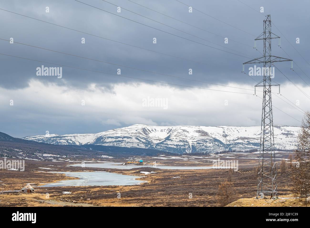 vista di un polo di linea ad alta tensione sullo sfondo di un paesaggio alpino ghiacciato Foto Stock