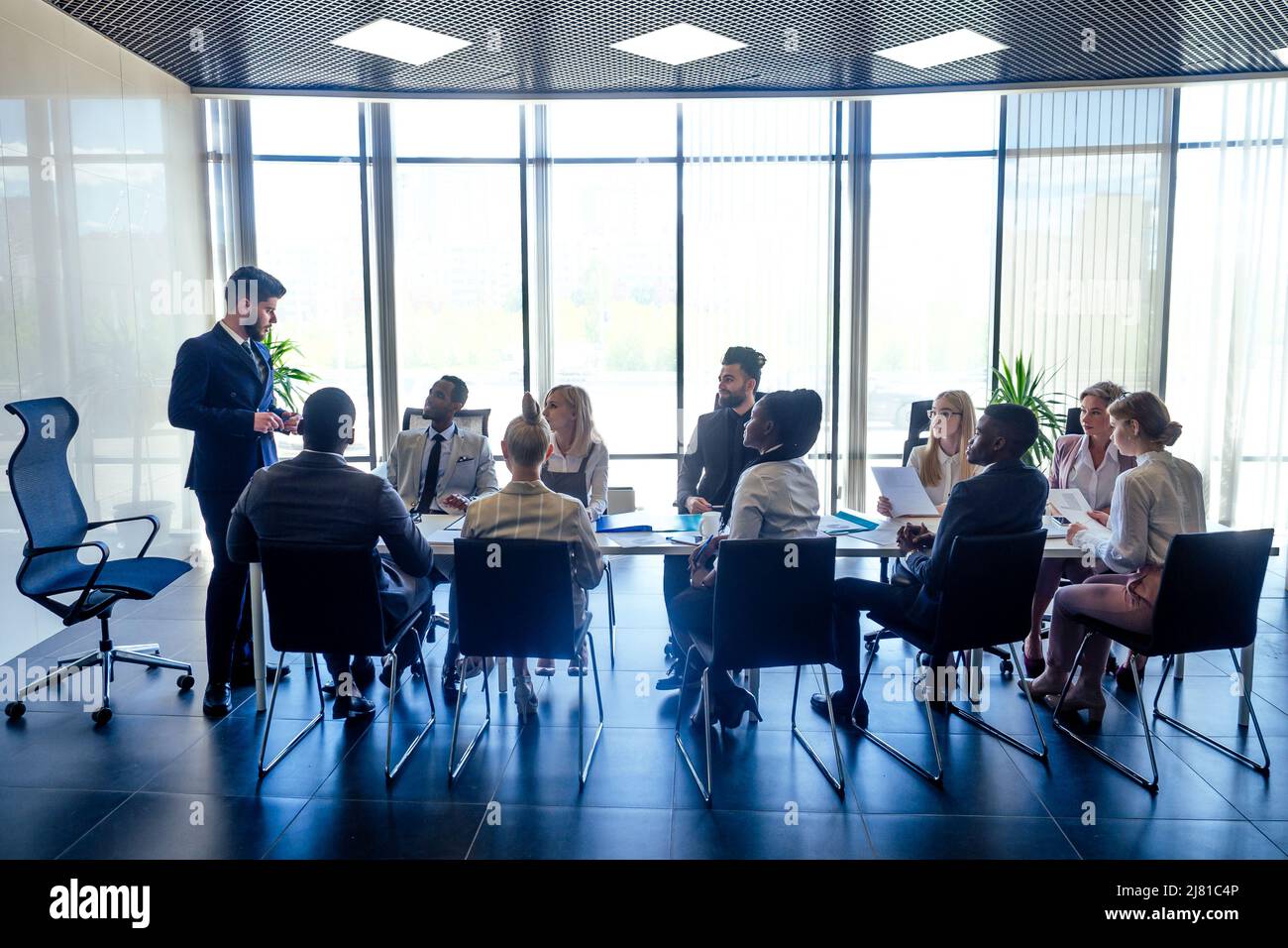 un gruppo di successo afro americani, europei, arabo e coreano uomo d'affari e donna d'affari che lavorano in ufficio con grandi finestre di vetro Foto Stock