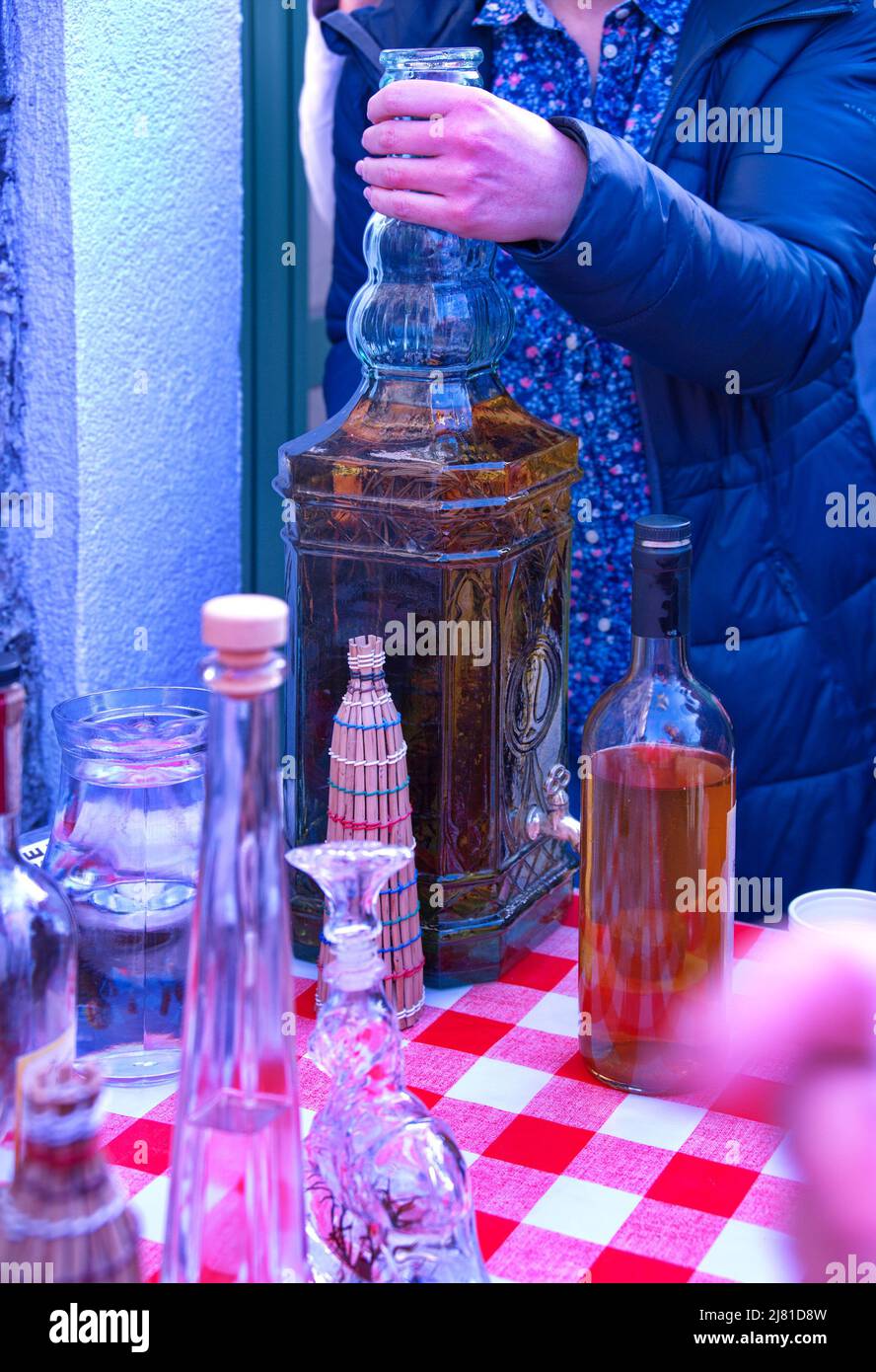 Sezione centrale della donna che tiene una bottiglia grande di brandy Foto Stock