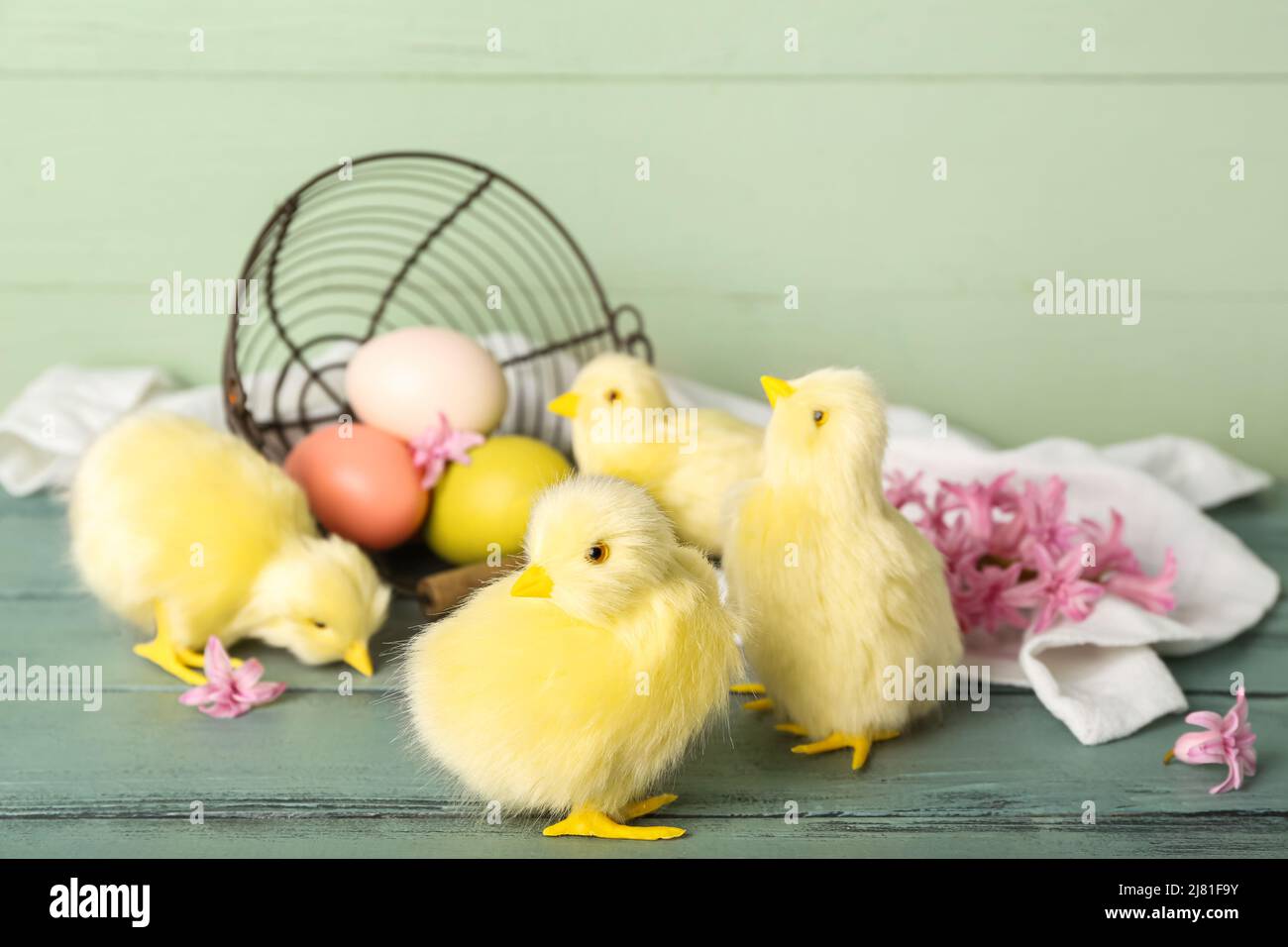 Polli carini, cestino rovesciato con uova di Pasqua e fiori su tavola di legno Foto Stock