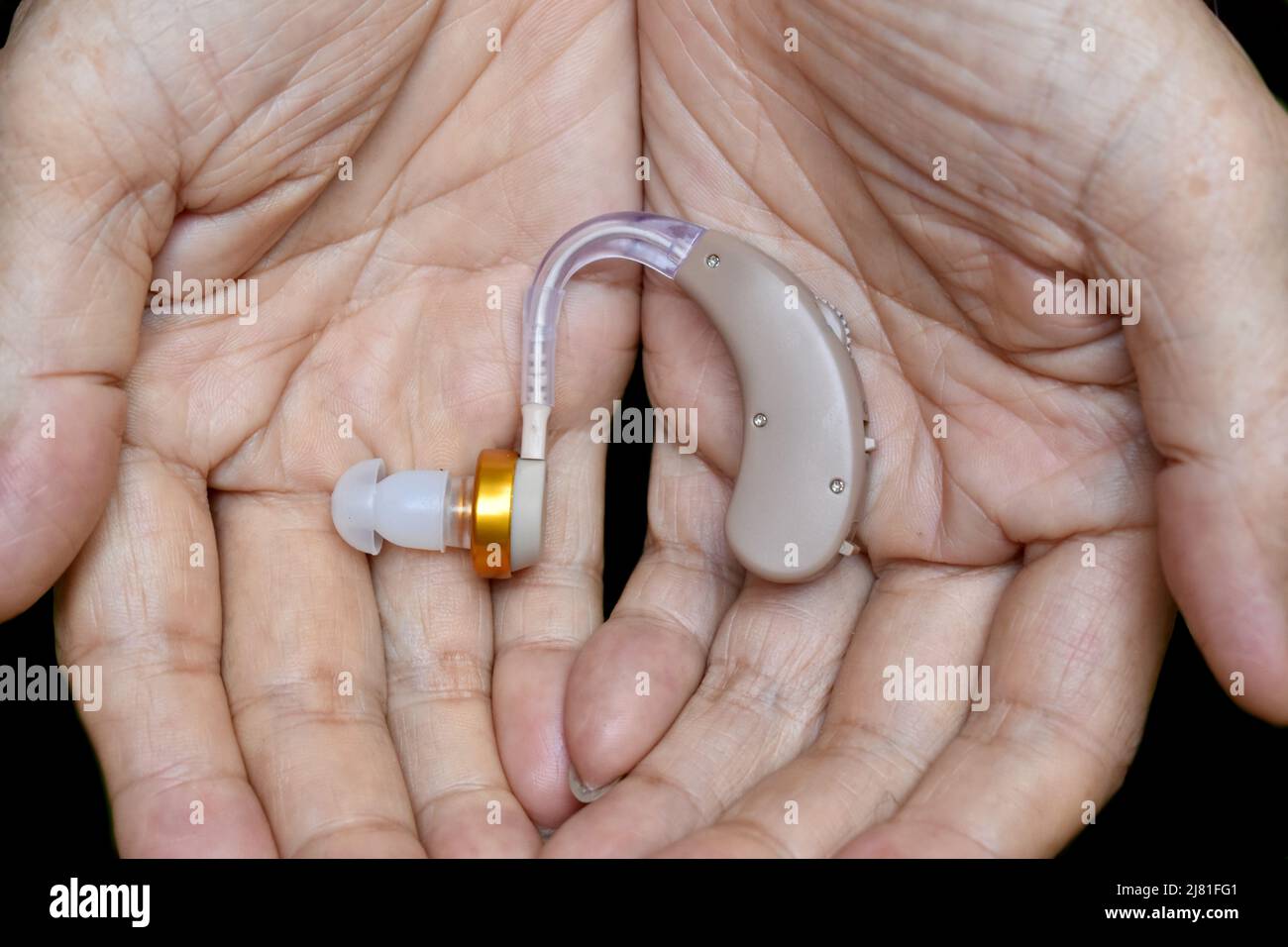 Apparecchio acustico elettronico nell'orecchio del vecchio asiatico con totale sordità. Foto Stock