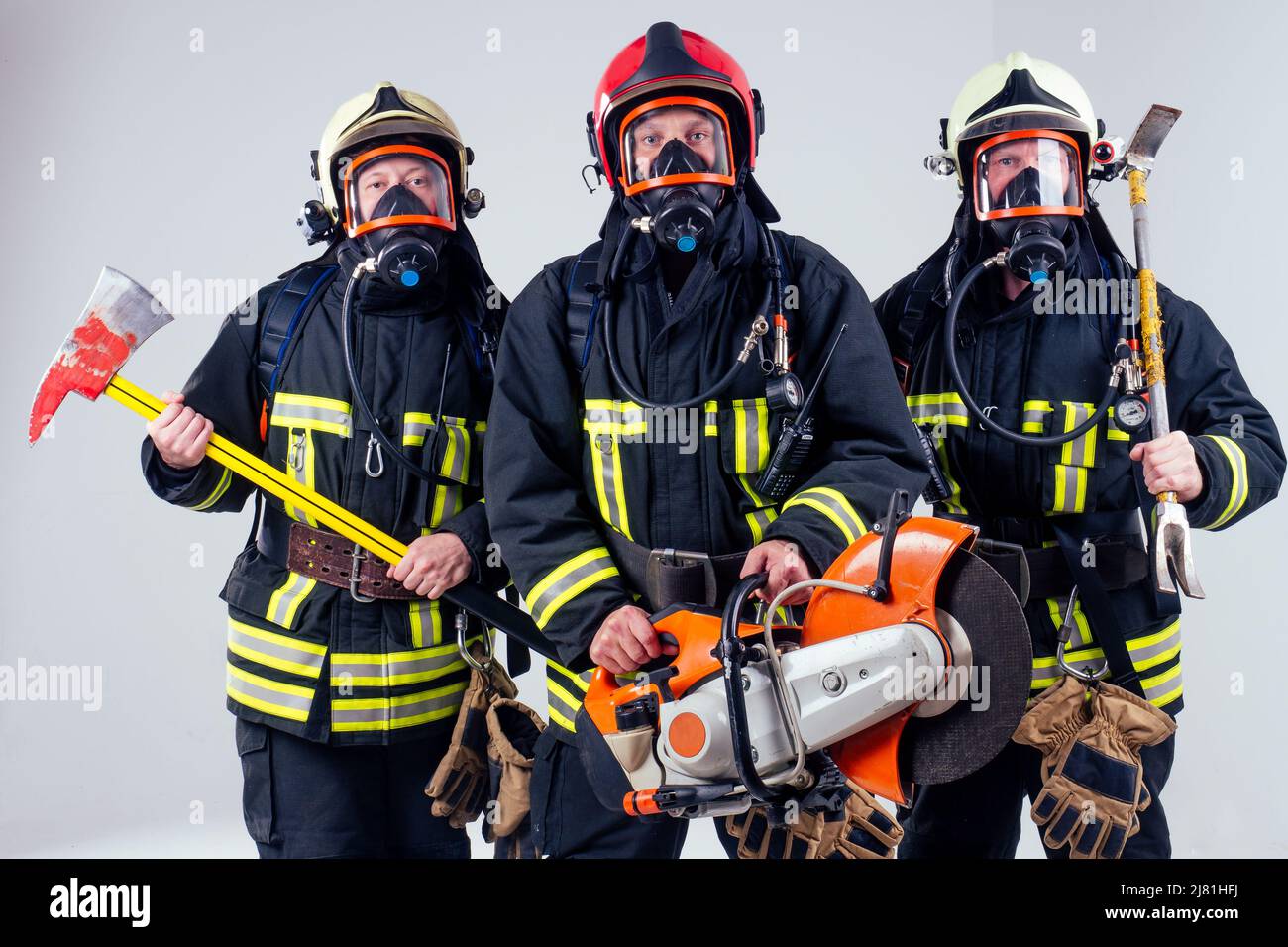 Ritratto di tre vigili del fuoco in piedi insieme bianco sfondo studio Foto Stock