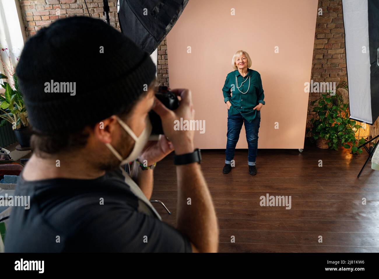 Giovane fotografa che prende i picure della donna anziana, backstage di photographing in studio. Foto Stock