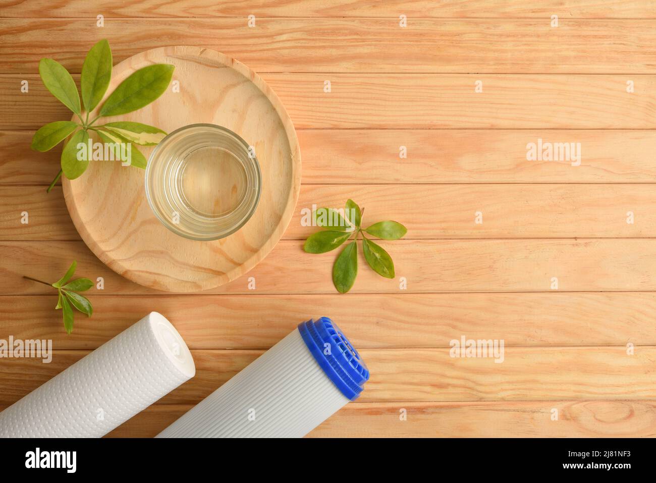 Sistema ad osmosi inversa concetto di purificazione dell'acqua con vetro riempito con acqua purificata e filtri su tavola di legno. Vista dall'alto. Composizione orizzontale. Foto Stock