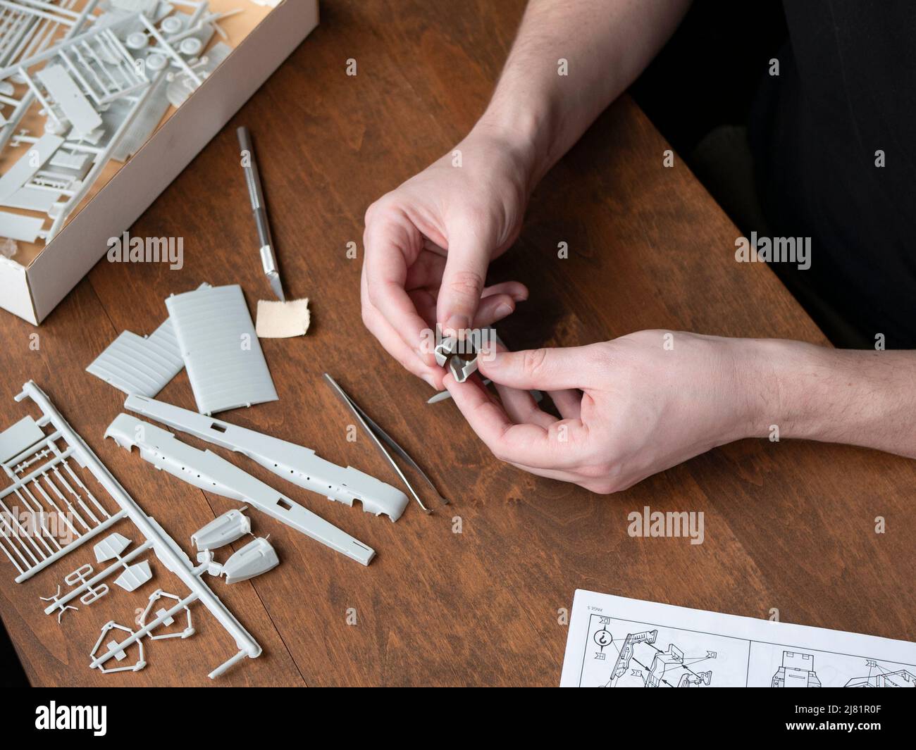 Il costruttore di modelli mette insieme i pezzi della fusoliera in plastica, fuoco selettivo. Fase di costruzione di velivoli modello in plastica Foto Stock