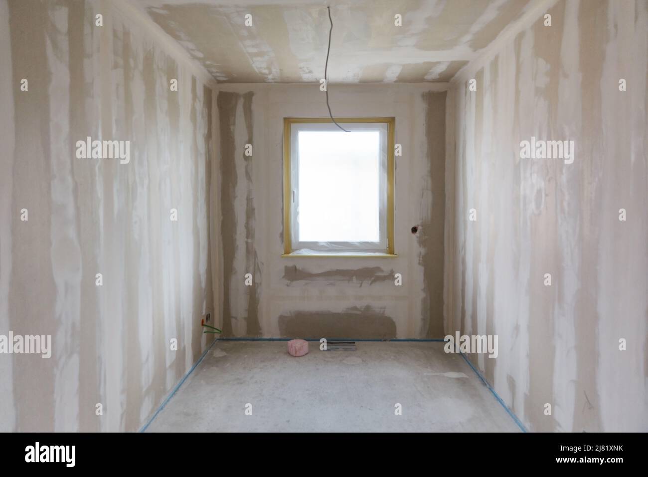 Finestra in una piccola stanza durante il lavoro della spatola durante il disegno interno durante la costruzione della casa Foto Stock