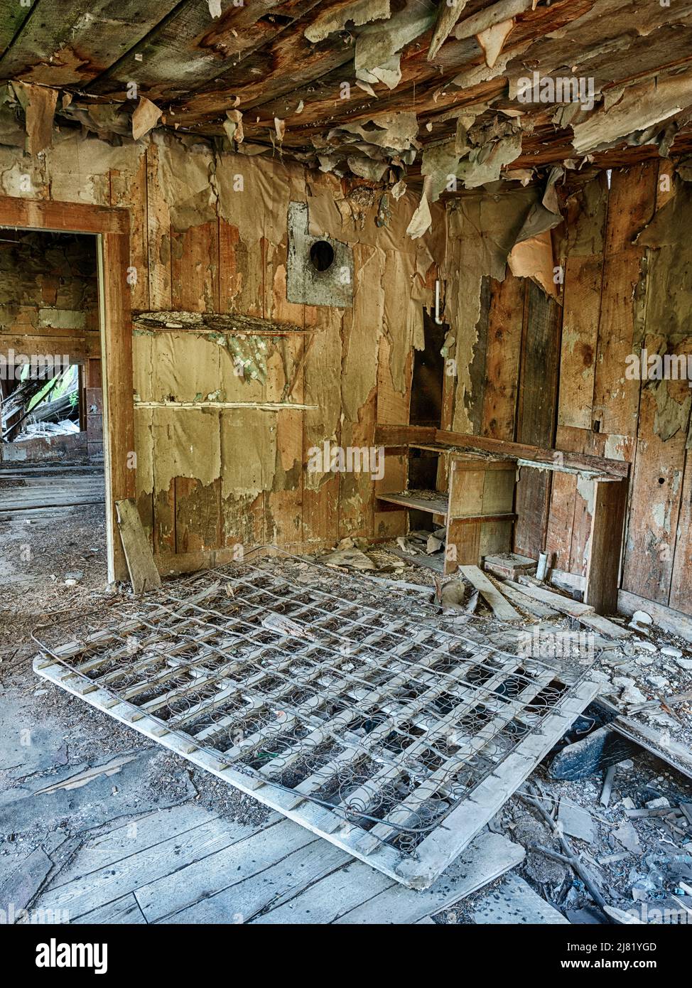 Una stanza vuota mostra la carta da parati peeling e alcune molle del materasso nella città fantasma di Bodie, Washington. Foto Stock