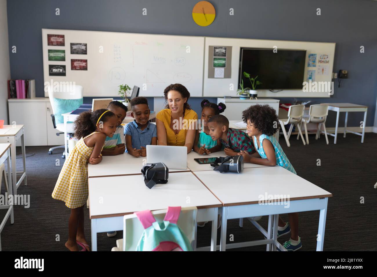 Giovane insegnante caucasica laptop insegnamento a studenti elementari afroamericani in classe Foto Stock