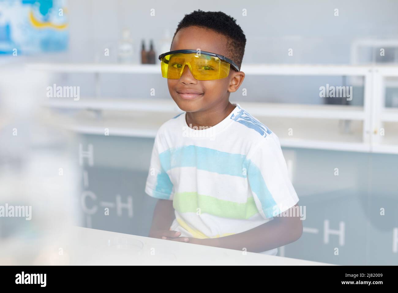 Ritratto di scuola elementare afroamericana indossando occhiali protettivi durante la classe di chimica Foto Stock