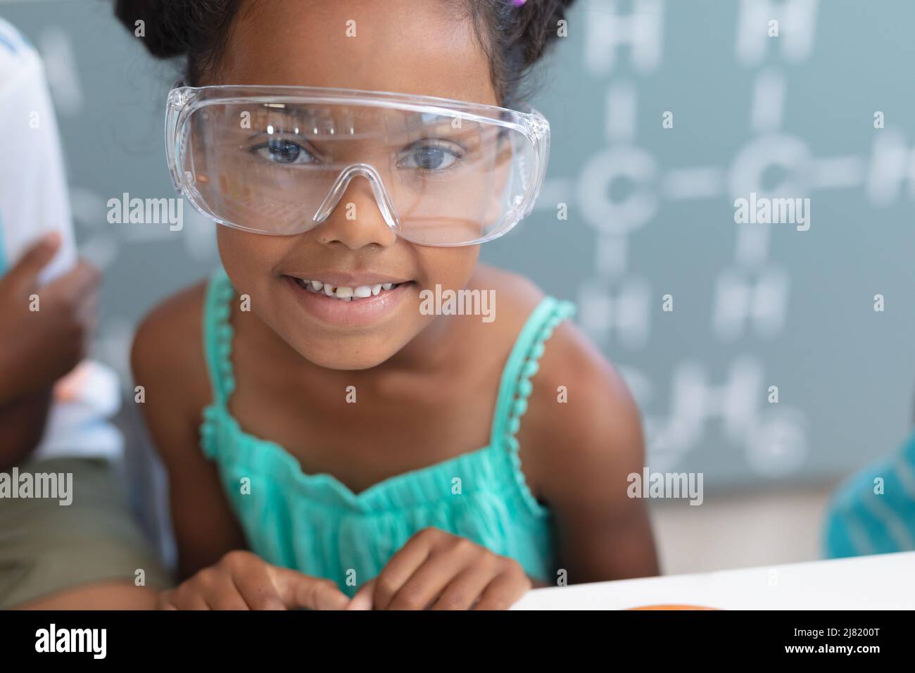 Ritratto di scolaretta elementare afroamericana sorridente che indossa occhiali protettivi in laboratorio Foto Stock