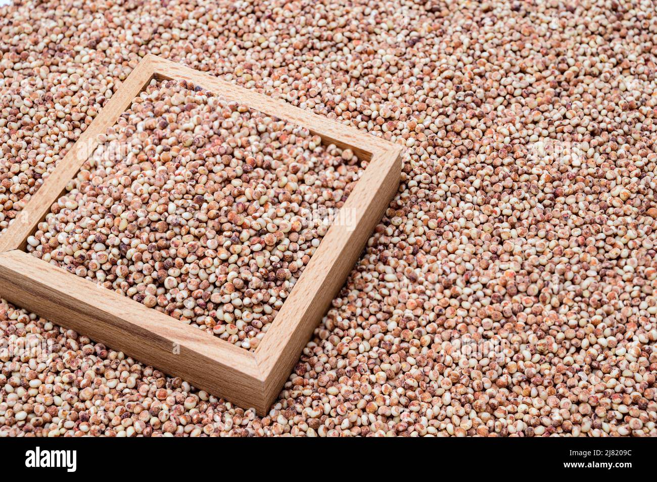 Un fondo con sorgo accatastato e una ciotola di legno contenente sorgo. Foto Stock