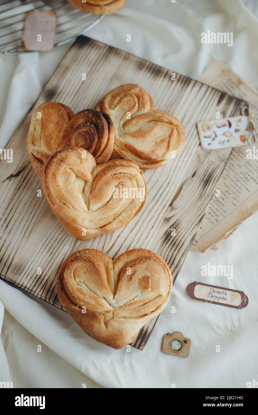 ciambelle dolci a forma di cuore con zucchero sul tavolo con un foglio di carta per la ricetta Foto Stock
