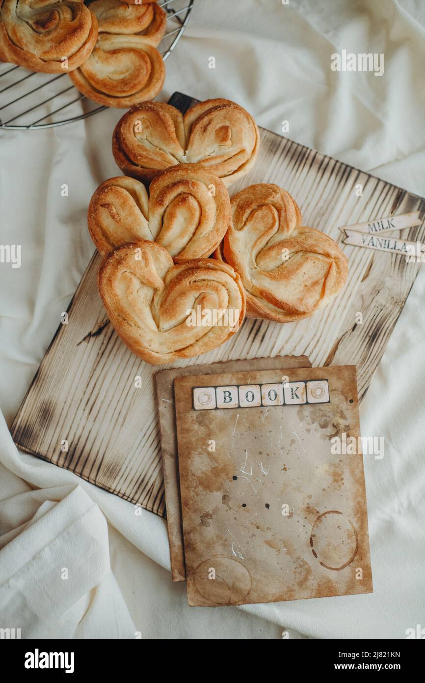ciambelle dolci a forma di cuore con zucchero sul tavolo con un foglio di carta per la ricetta Foto Stock