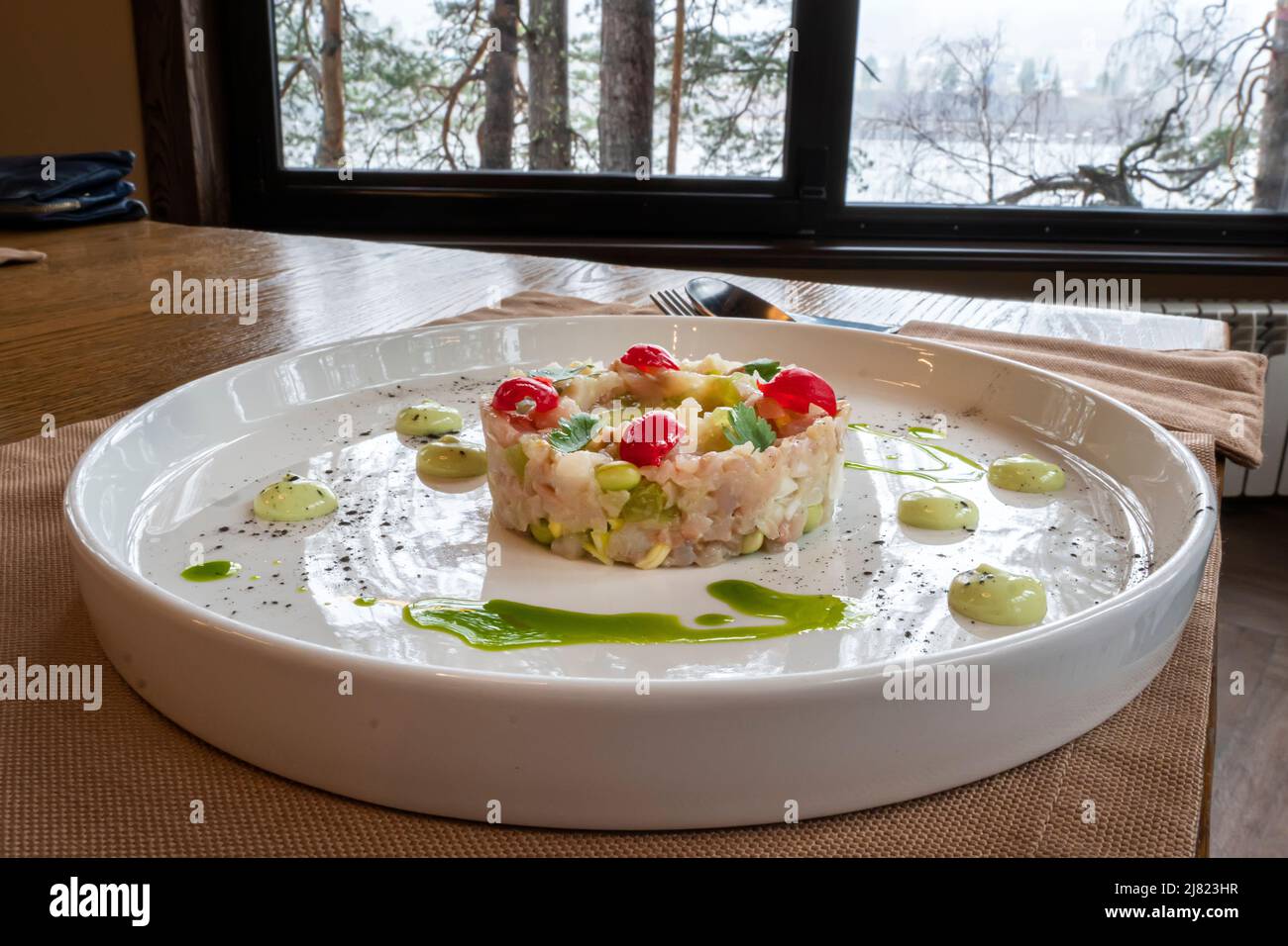 L'insalata di vari ingredienti è ben organizzata a forma di anello su un piatto bianco. Foto Stock