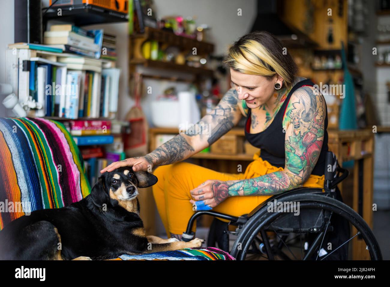 Giovane donna con disabilità con il suo cane a casa Foto Stock