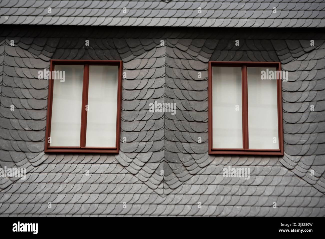 Due finestre circondate da numerose piastre in ardesia/pietra contro gli agenti atmosferici. Edificio a Francoforte sul meno, in Germania. Foto Stock