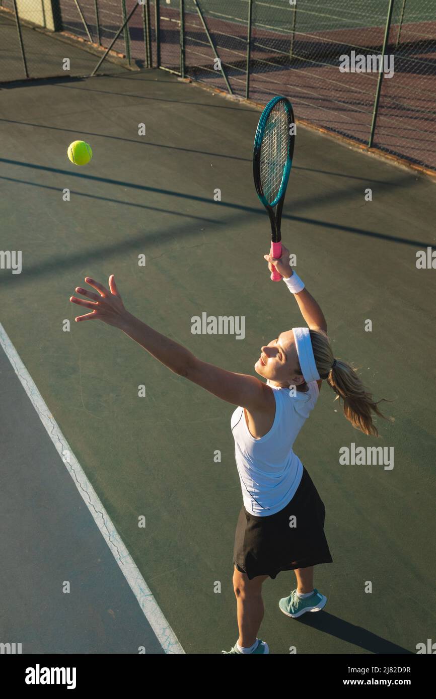 Vista ad alto angolo di giovane donna caucasica che serve durante la partita di tennis al campo Foto Stock