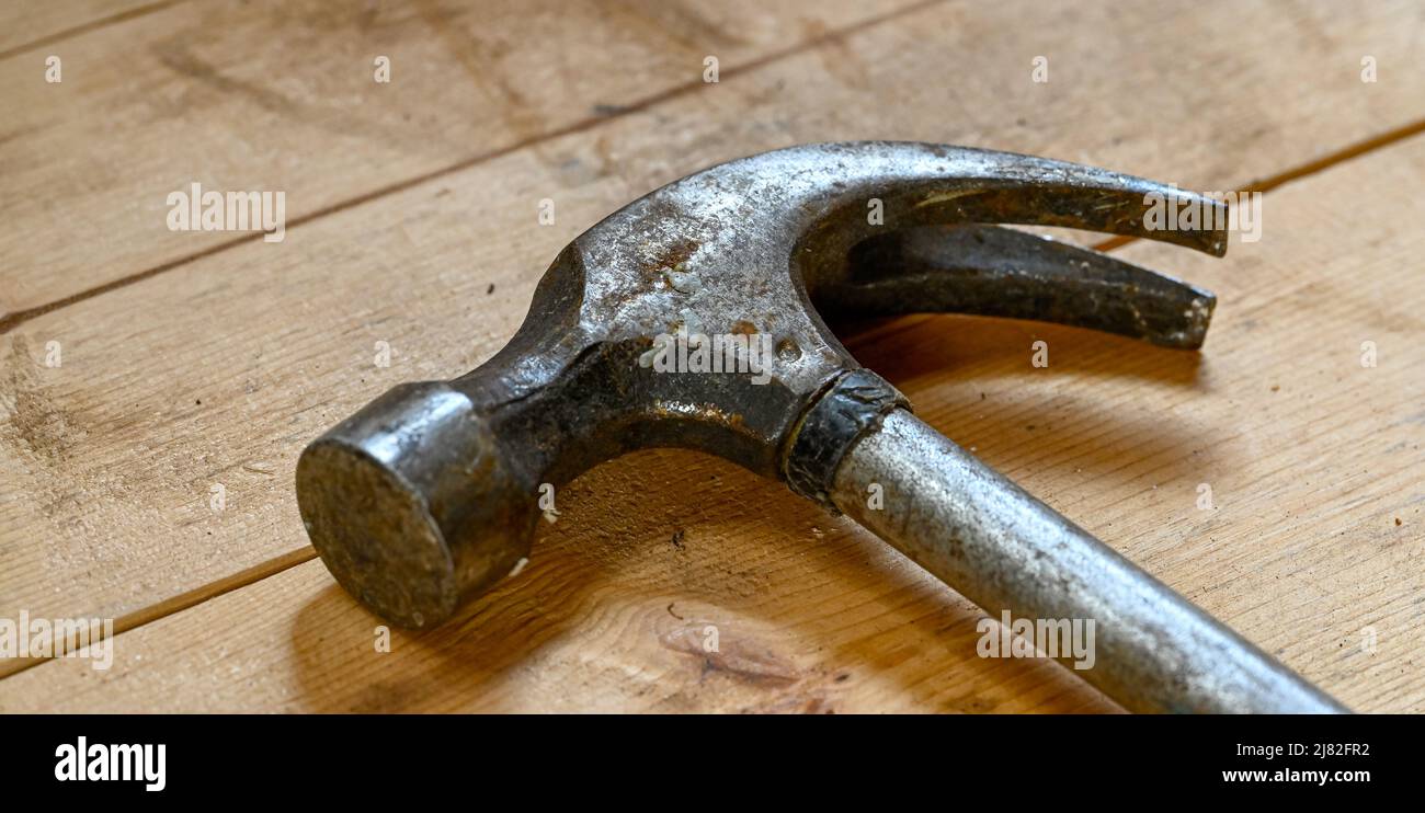 primo piano della testa del martello adagiata su un banco di legno Foto Stock