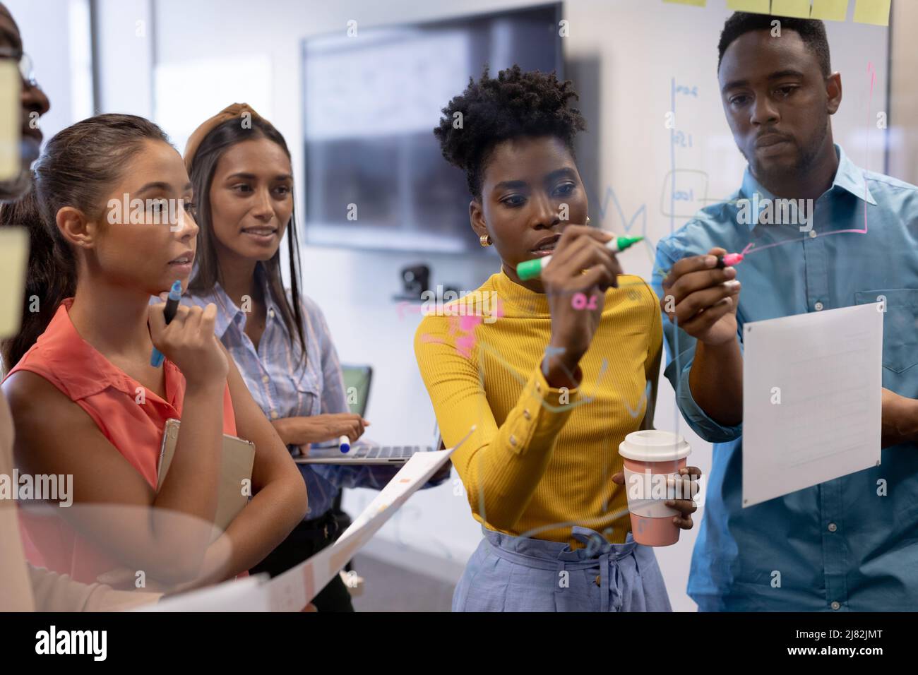 Consulente di sesso femminile e maschile per la pianificazione della strategia mentre si scrive su una parete di vetro nella sala riunioni Foto Stock