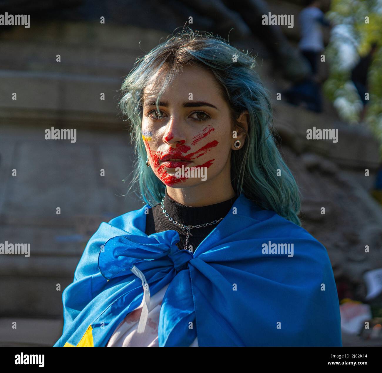 Ritratto di una donna attivista con bandiera nazionale Ucraina e tracciato traccia di una mano sanguinosa sul volto Foto Stock