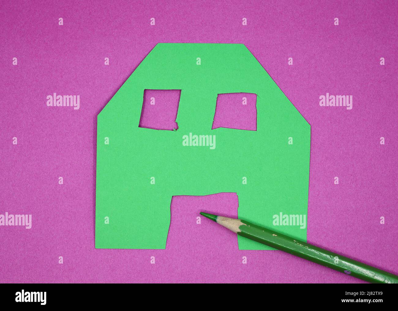 forma della casa di carta verde e pastello verde su sfondo rosa Foto Stock