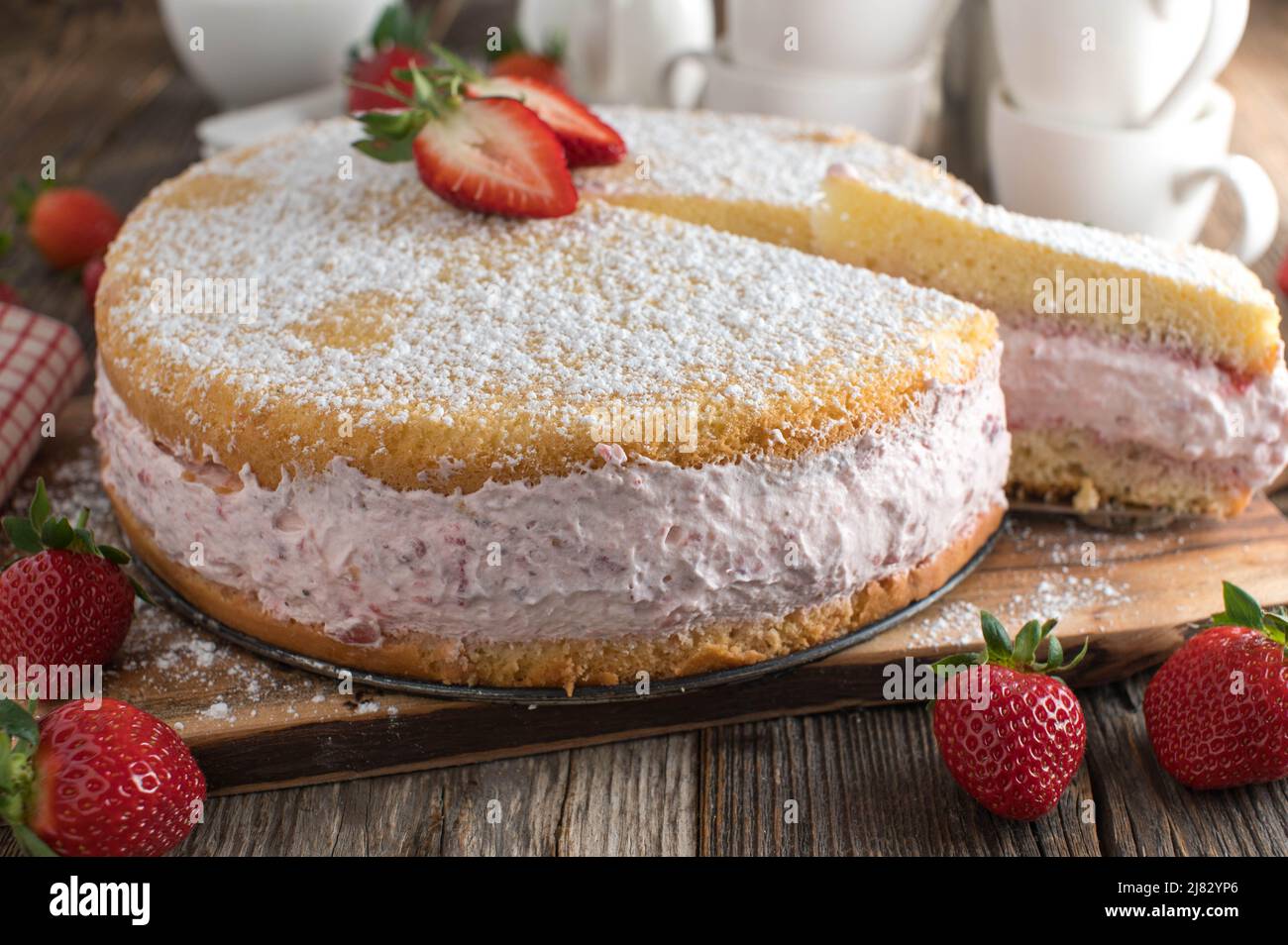 Torta di fragole con panna montata su sfondo rustico e tavolo in legno Foto Stock