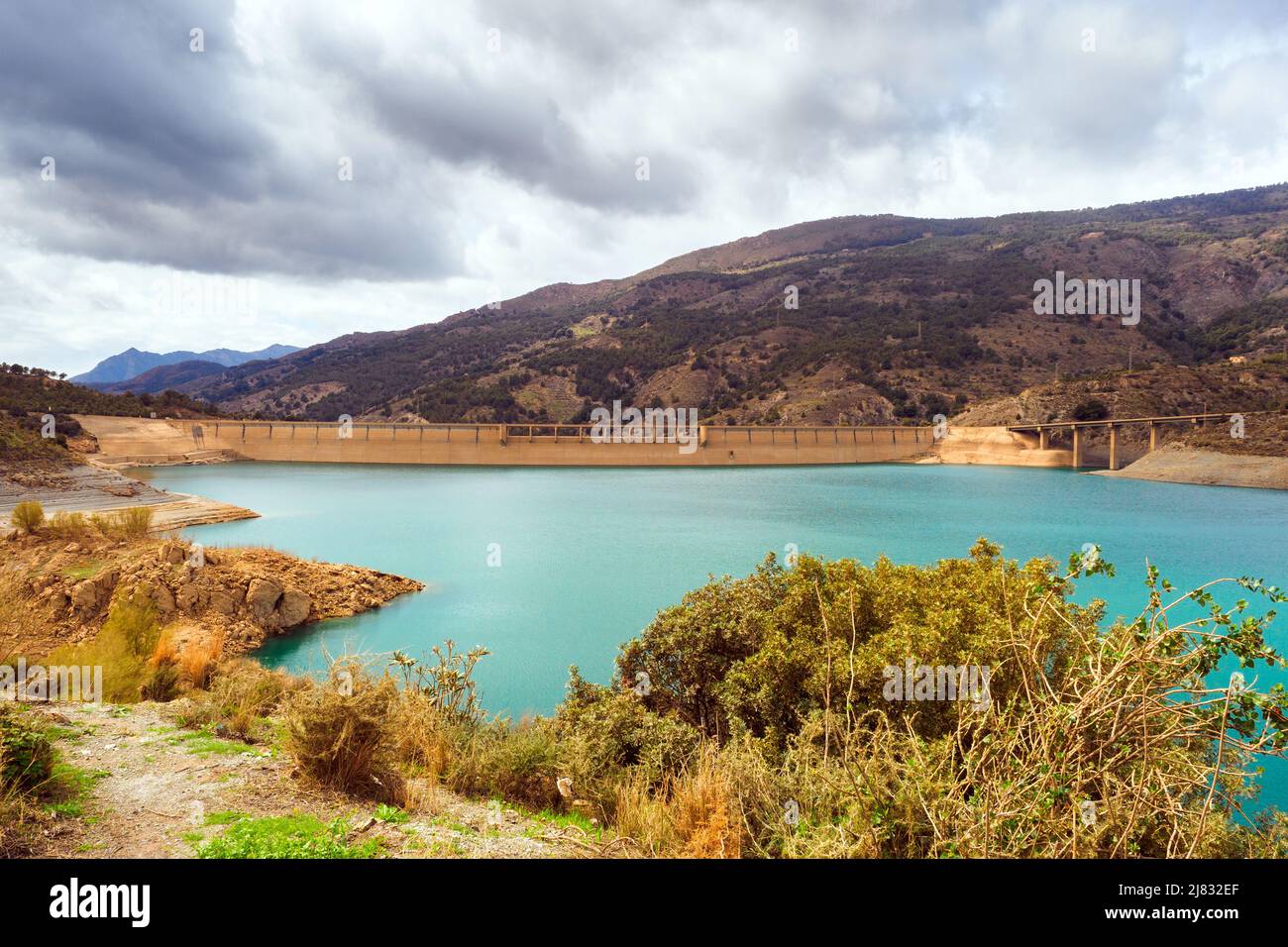 Il bacino di Béznar si trova a sud della Valle de Lecrin, sul fondo del fiume Ízbor. L'acqua che passa la diga va a Motril e Salobreña. Questo serbatoio è stato creato per alluvioni laminari e la produzione di energia idroelettrica - Andalusia, Spagna Foto Stock