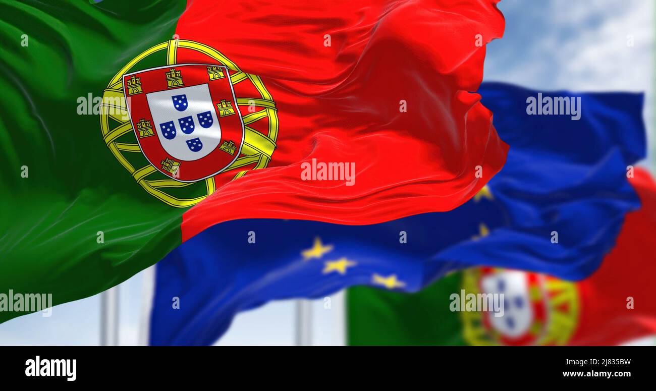 Dettaglio della bandiera nazionale del Portogallo che sventola nel vento con la bandiera dell'Unione europea sfocata sullo sfondo in una giornata chiara. Democrazia e politica. Foto Stock