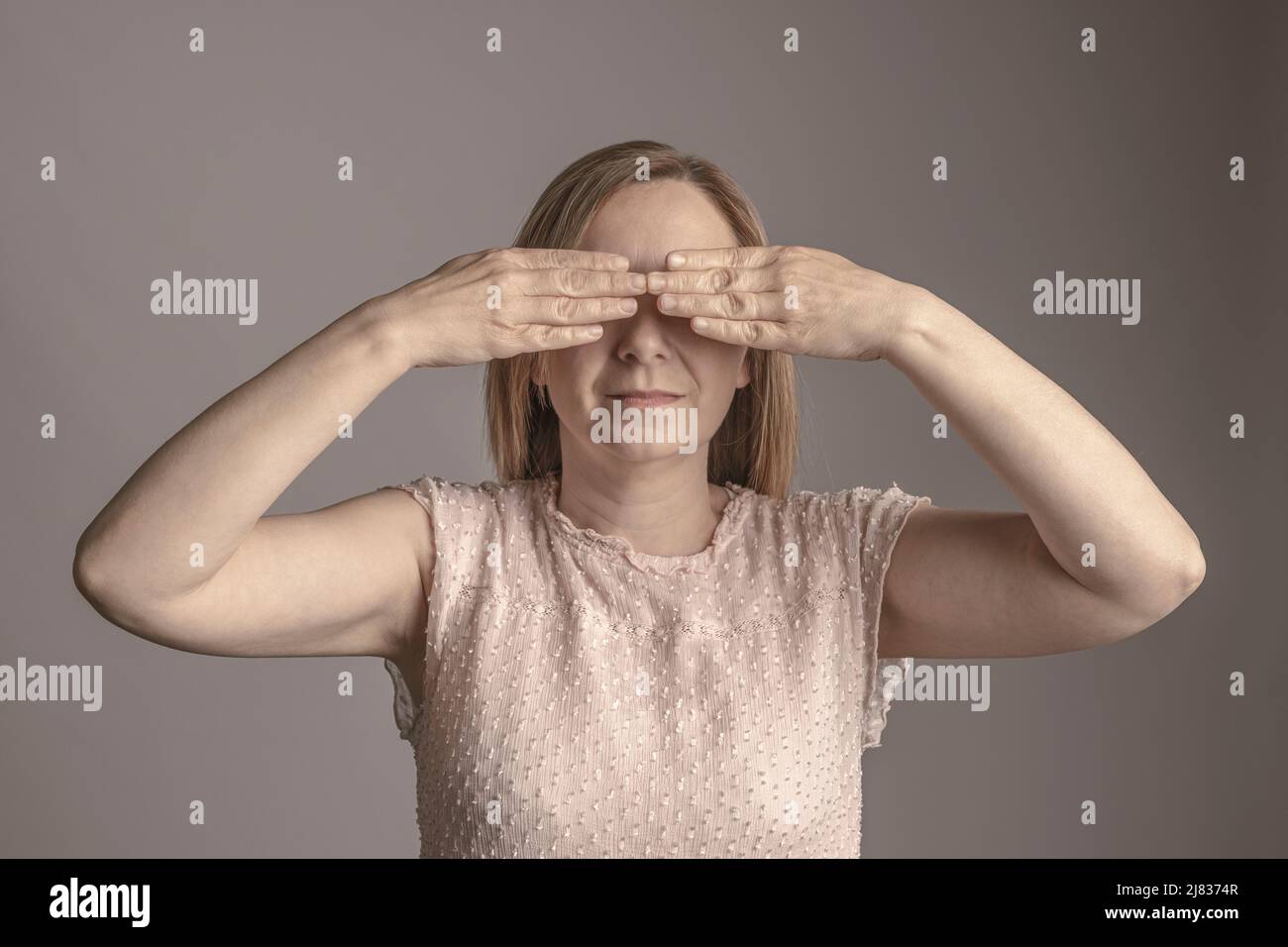 ritratto di donna che copre gli occhi con le mani Foto Stock