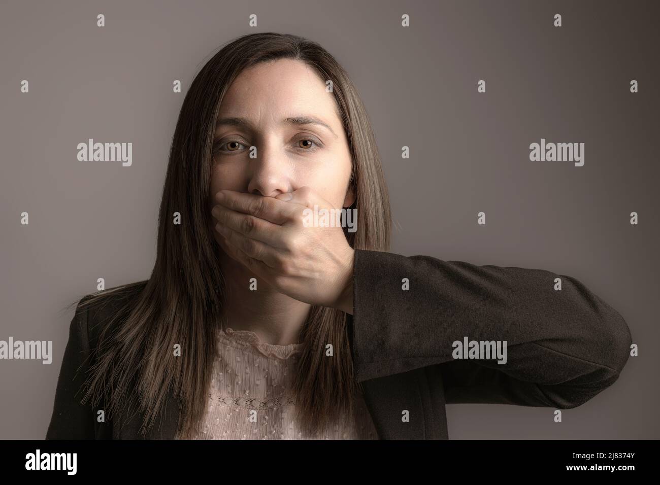 ritratto di una donna che ricopre la bocca con una mano. Foto Stock
