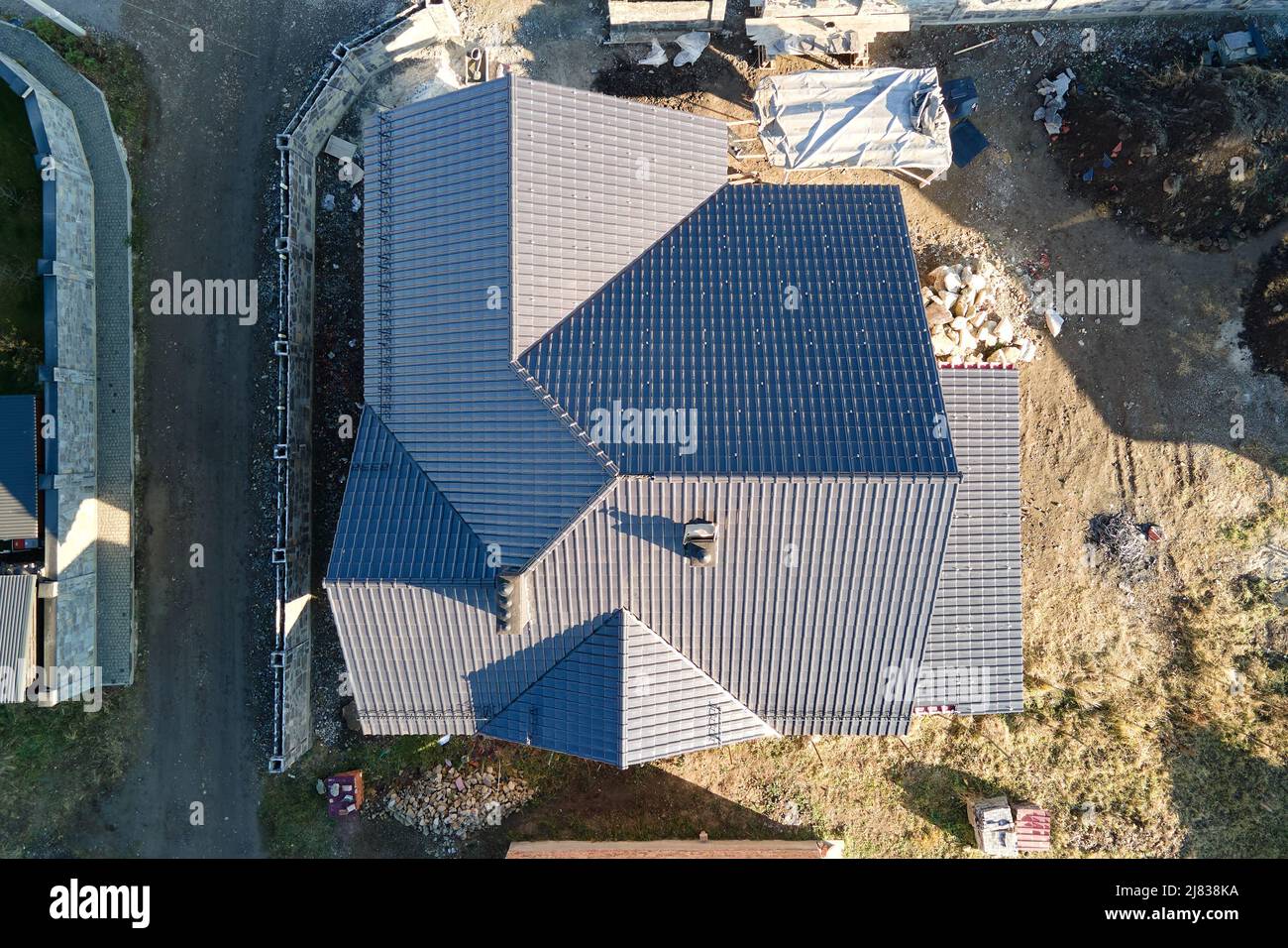 Camino sul tetto della casa coperto con scandole metalliche in costruzione. Rivestimento piastrellato dell'edificio. Sviluppo immobiliare Foto Stock