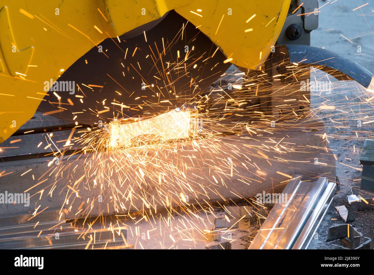 Un operaio di costruzione che sega attraverso aste di acciaio strutturale galvanizzato per la costruzione di cornici interne. Foto Stock