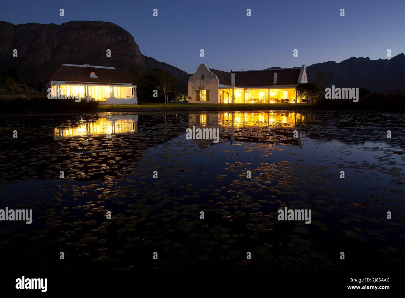 Riflessioni notturne: Cielo stellato e Villa la cotte illuminata sul lago Foto Stock