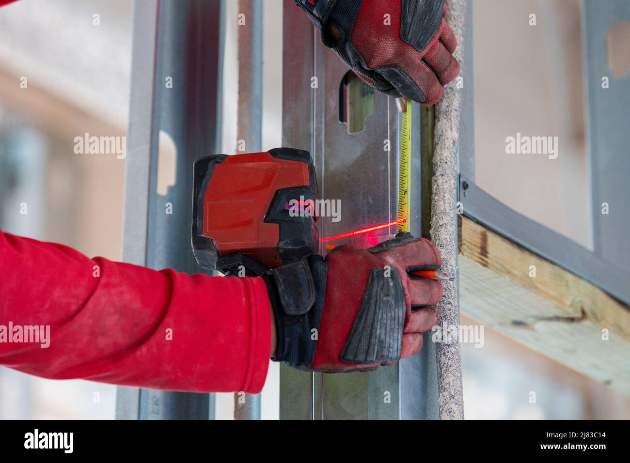 Costruzione misurazione laser Framer per il successivo puntone in acciaio zincato da montare e installare. Foto Stock