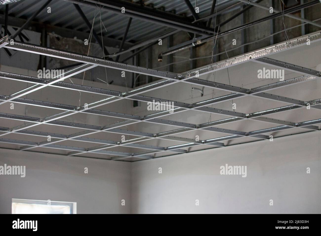 vista interna di un edificio commerciale durante la costruzione con un soffitto di piastrelle a scomparsa, che mostra pareti in cemento struttura metallica, muro a secco e tetto in metallo Foto Stock