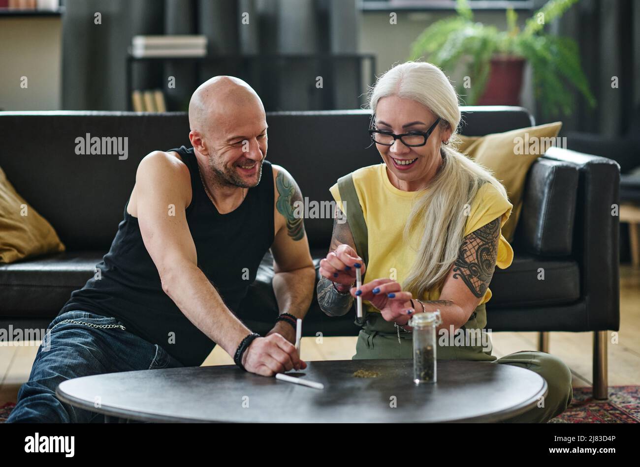 Moderno uomo caucasico maturo e donna arrotolare sigarette fatte a mano con marijuana, concetto di trattamento della cannabis Foto Stock Moderno uomo caucasico maturo e donna arrotolare sigarette fatte a mano con marijuana, concetto di trattamento della cannabis Foto Stock