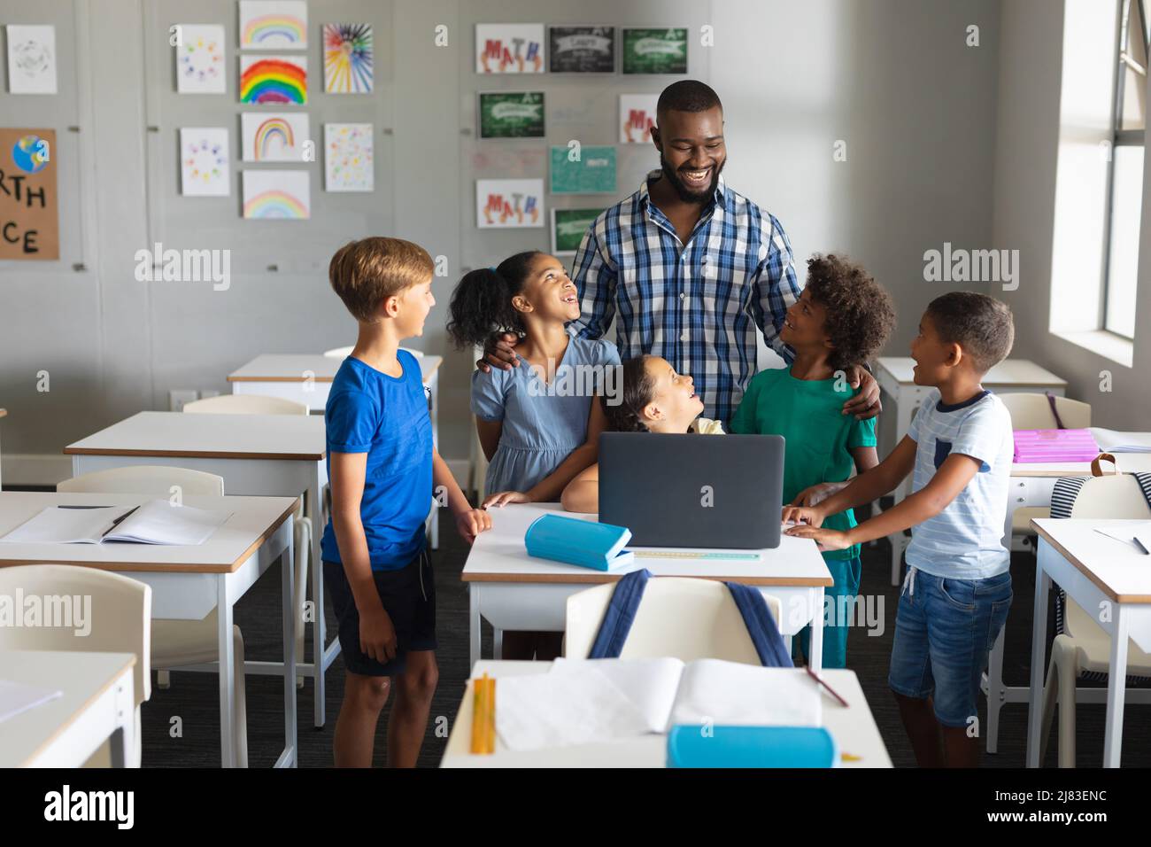 Felice africano americano giovane insegnante maschile laptop insegnamento a studenti elementari multirazziale Foto Stock