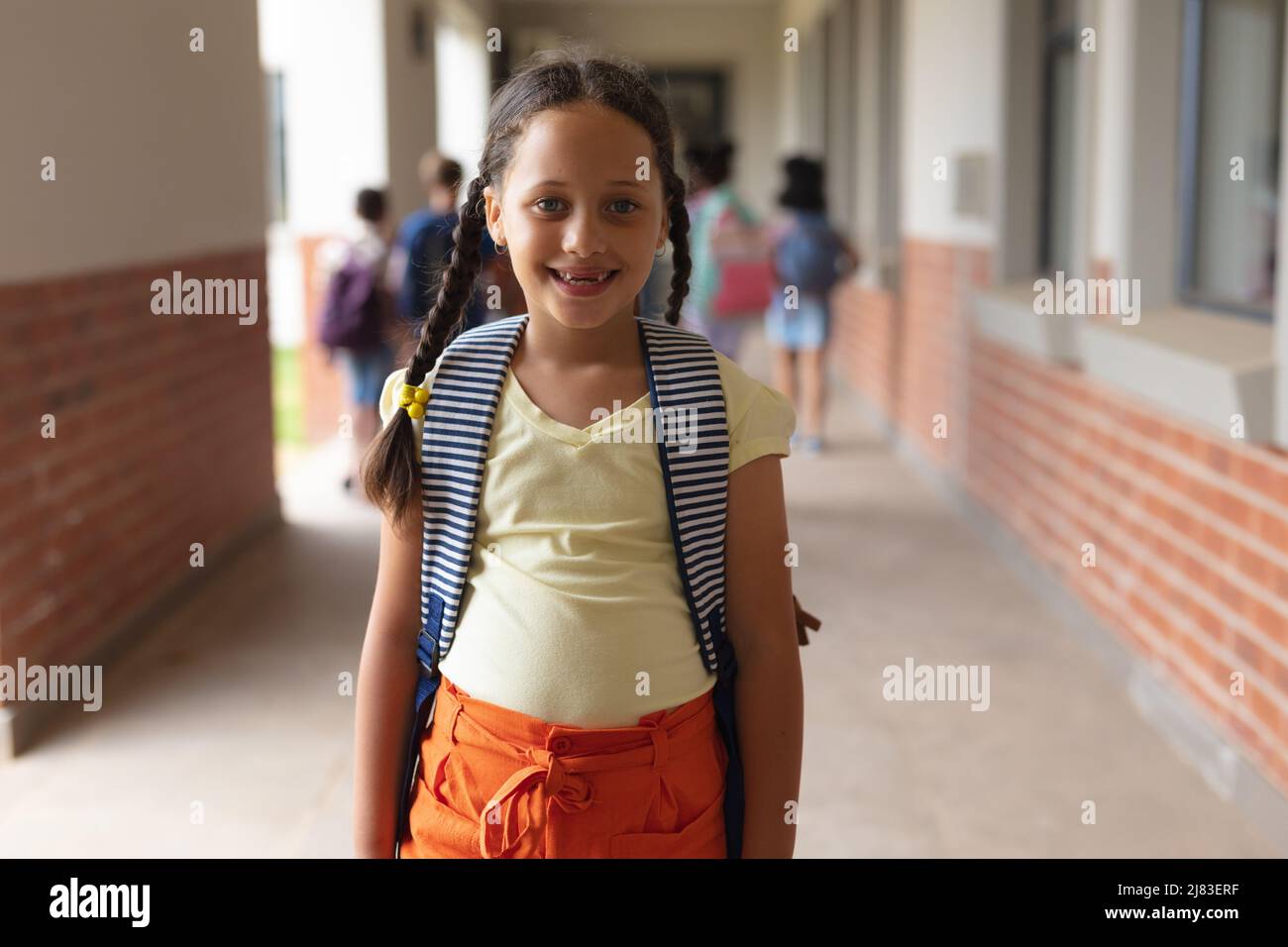 Ritratto di felice scolaretta caucasica elementare in piedi in corridoio Foto Stock