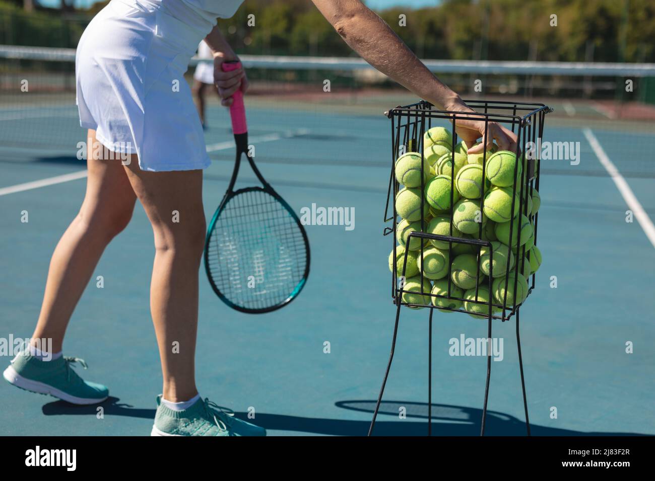 Bassa sezione di giovane donna caucasica che pratica il tennis in campo in giornata di sole Foto Stock