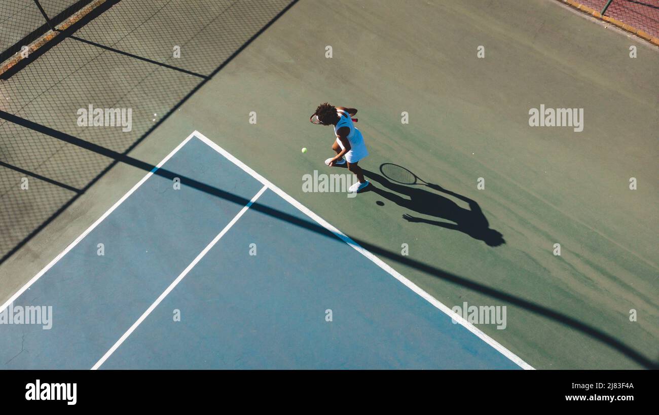Vista ad alto angolo di una donna afro-americana che serve durante la partita di tennis in campo il giorno di sole Foto Stock
