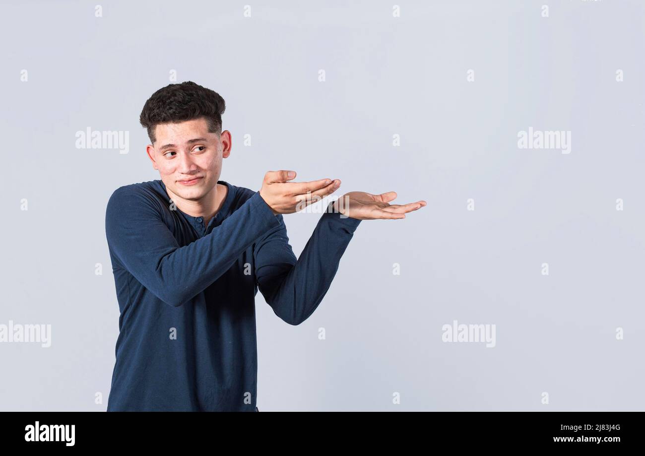 Bell'uomo che punta le palme sul lato, ragazzo amichevole che punta le mani sul lato, giovane uomo che punta le palme sullo spazio vuoto, persona che punta alla bandiera Foto Stock