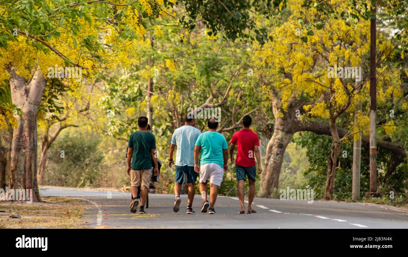 01 maggio 2022, Prayagraj Uttapradesh, un gruppo di uomini fuori per una passeggiata mattutina su una bella strada fiorita. Foto Stock