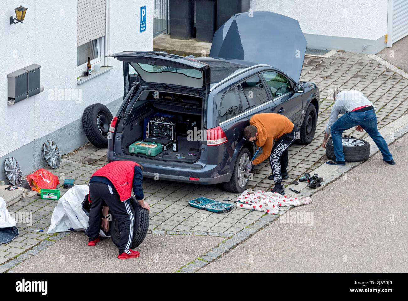 Cambio pneumatici per la stagione, cambio inverno a estate, uomo cambio pneumatici su auto, inverno pneumatici, estate pneumatici, Germania Foto Stock