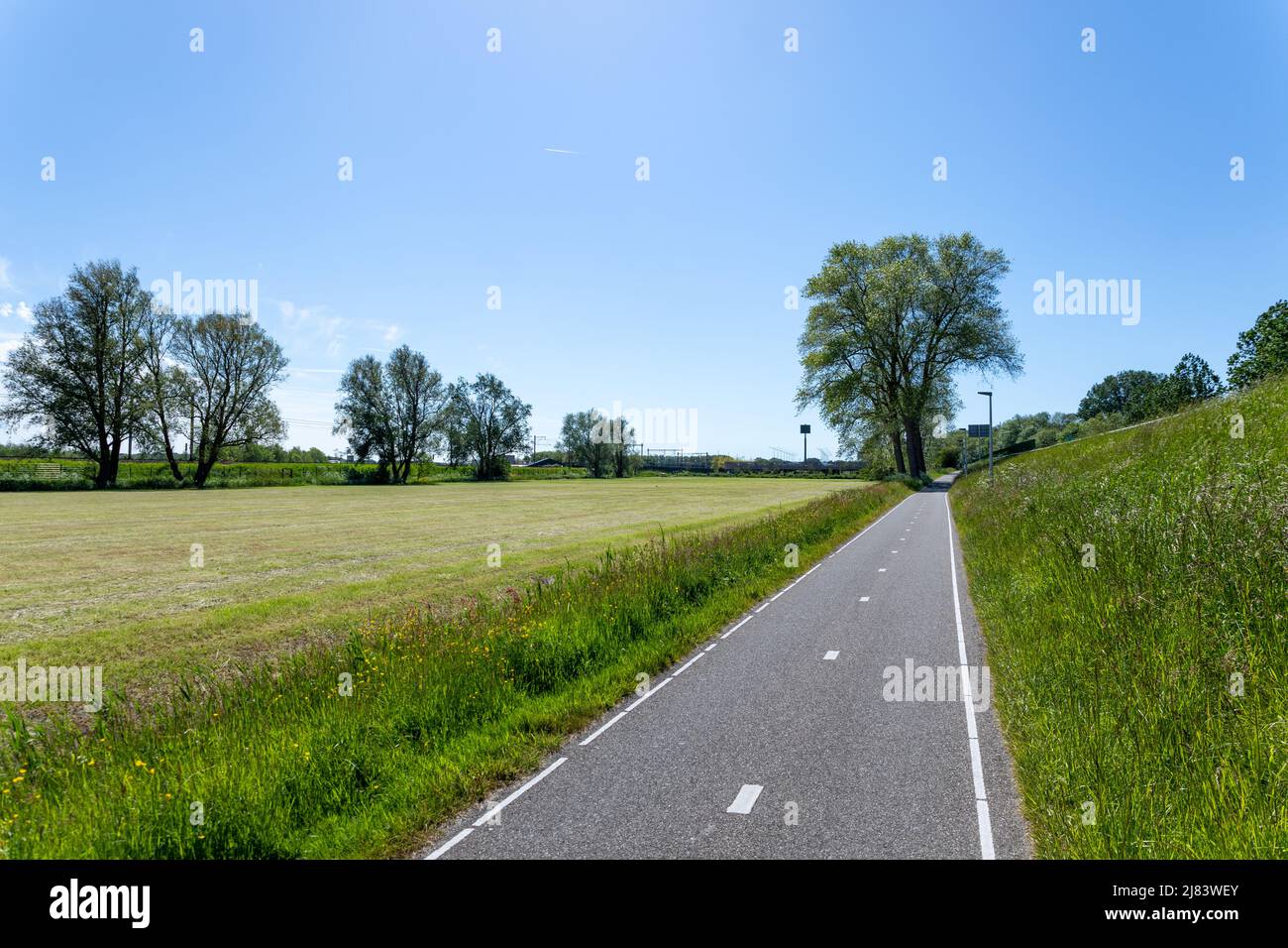 Un percorso ciclabile asfaltato a 2 corsie lungo la A44 e i prati appena rasati verso la stazione ferroviaria di Sassenheim nel comune di South-Holland di Foto Stock