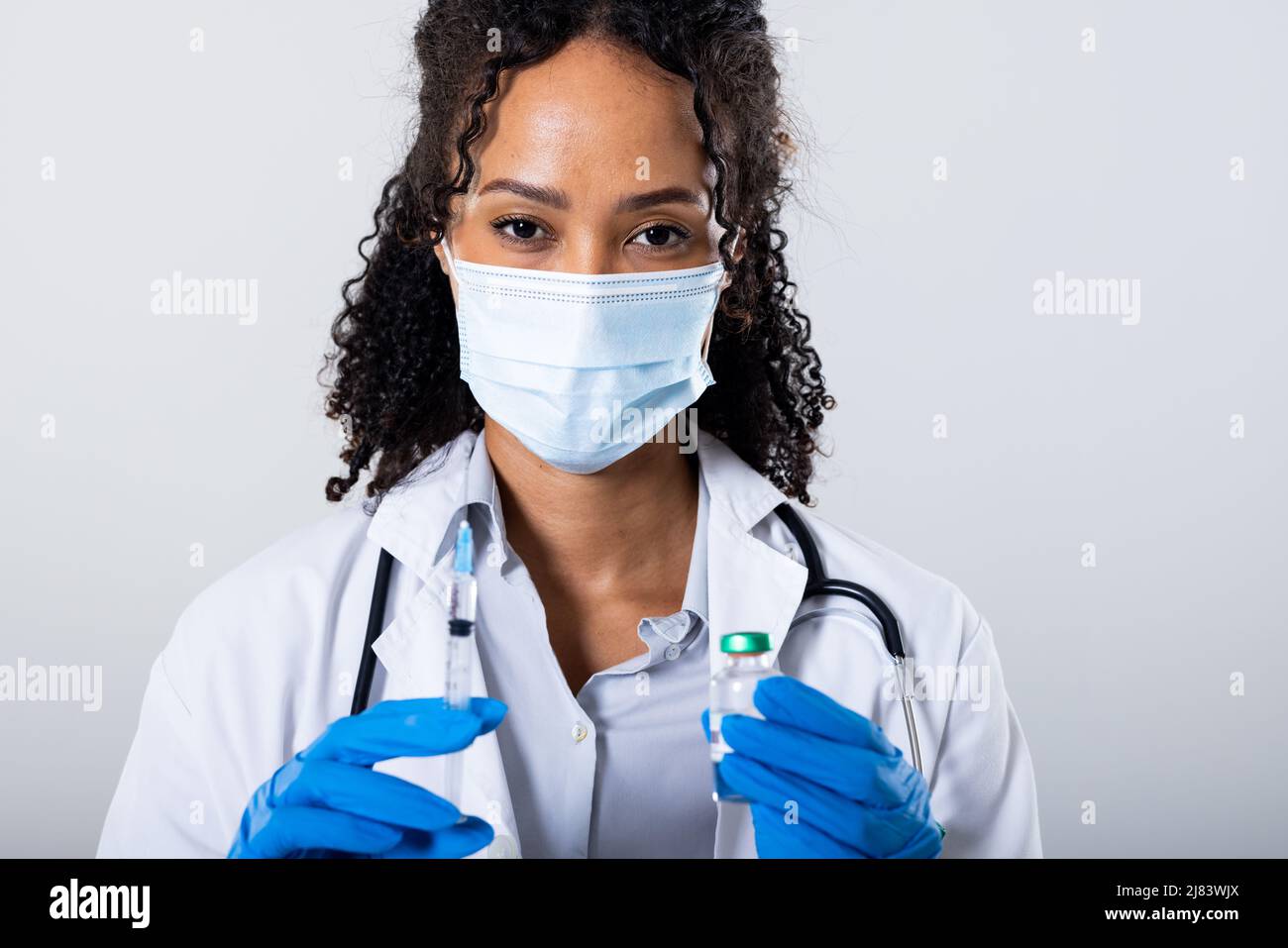 Ritratto di african american MID adult femmina medico indossare maschera di tenuta siringa, flaconcino, spazio copia Foto Stock